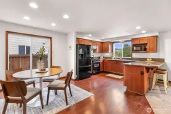Closer view of the dining and kitchen.  Cherry finish on all trim & cabinets with black appliances.  Kitchen has a view of the nature greenbelt beyond the backyard.