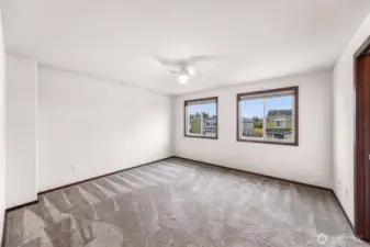 One of the 3 bedrooms (bedroom #1).  This bedroom is the larger one other than the primary suite.  With two west facing windows, a light/fan fixture, and a walk in closet to your right.