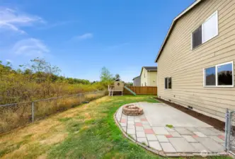 Outside!  Greenbelt to your left along chain link fencing, playhouse in the far corner and a large patio with a firepit waiting for your fall decor/furniture.  Don't miss the fenced area to your right...
