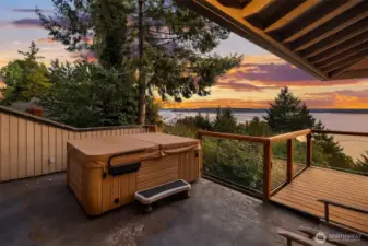 Upstairs deck off of the primary bedroom features a hot tub, glass paned railings and extra storage with a beverage refrigerator.