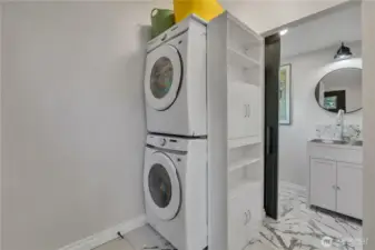 Way back to the kitchen and by the back door, you will find this laundry room and half bath with built-in shelving over and beside the stacking full-size units.