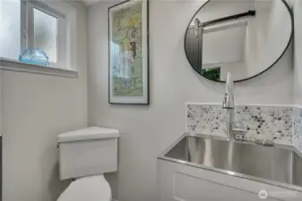 Powder room with a sliding barn door and a deep stainless sink that doubles as a classy utility sink for your day to day needs.  Heated floors extend throughout.