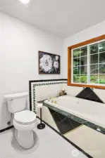 Tub in primary bath with new flooring, new toilet and lots of natural light.