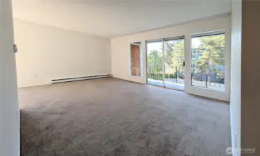 Living area with large windows and sliding door to allow a lot of light. Sliding door opens to balcony. Freshly painted