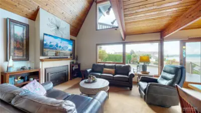 Cozy family room with vaulted wood ceilings, gas fireplace, and large windows showcasing lake views.