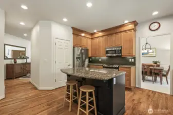 The informal areas are one contiguous space and feature an updated kitchen with maple cabinets with soft close drawers and doors, slab granite counters, an island with seating, stainless steel appliances including a gas range and a walk-in pantry.
