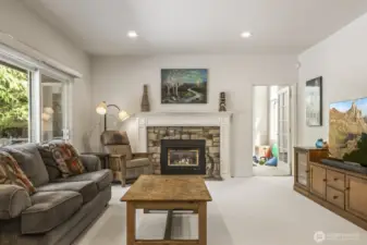 The informal gathering room features a stone surround gas fireplace and sliding door to the deck.