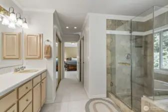 The primary suite with crown molding and tranquil backyard views features 2 walk-in closets and an updated 5 piece bathroom with soaking tub, tiled shower, dual vanities and tile floor.