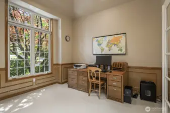 French doors lead into the office that features  wood wainscoting.
