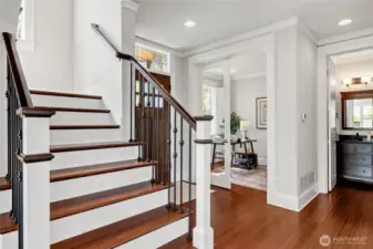 Stairs lead to the upper level. The home office in the background. Not pictured is the main floor powder room.