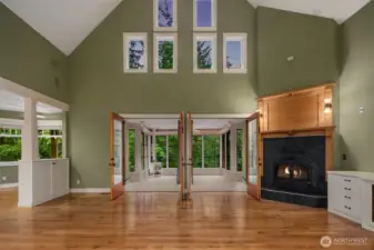 Two story living room with high-efficiency wood burning fireplace insert with blower, slate surround with custom mantle including built-in media cabinetry