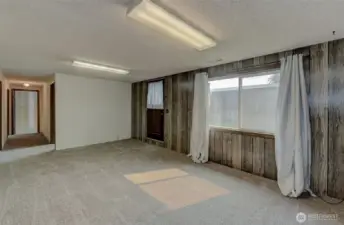 Large family room in basement with door to the backyard.