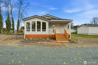 Front view showcasing the large picture windows that fill the home with natural light and a welcoming covered entry.