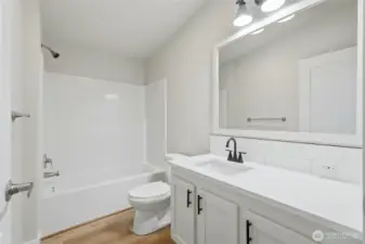 The full bathroom features a contemporary vanity design and utilizes a palette of clean, modern tones throughout the space, creating a fresh feel.