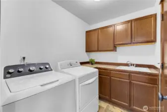 laundry conveniently located off garage with utility sink and cabinets for storage