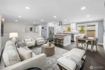 A short, easy flight of stairs lifts you into the heart of the home, where the main level opens into a bright, cohesive living space. The living room, dining area, and kitchen flow together effortlessly, creating a natural sense of connection throughout. High ceilings enhance the feeling of spaciousness overhead, while updated recessed lighting casts a soft, even glow that makes the entire level feel welcoming and expansive. New luxury vinyl flooring runs throughout the main living areas, designed with a rich hardwood tone that adds warmth and depth underfoot while maintaining a clean, modern feel. The layout allows each space to feel connected yet comfortably defined, creating an atmosphere that naturally brings people together.