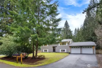 This charming home instantly feels inviting with its classic cheerful shutters and lush landscaping. Nestled among tall evergreens, it exudes a cozy, homey feel that’s both welcoming and serene. The landscaping has been beautifully refreshed, featuring a wide lawn that is shielded from street view by trees. Mature flowering shrubs and trees provide easy maintenance and year-round enjoyment.