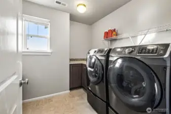 Dedicated laundry room with storage and counter space for added convenience.