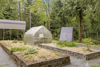 View of the greenhouse, raised beds and one of the treehouses...
