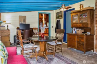 Studio/Solarium with side door out of picture to the right and behind, blue door from garage, and open doorway into LR and kitchen area. Radiant heat is not in this section of the home. Previous owner had erected a wall to make two small offices that present owner removed. Clear roofing material is covered with wood above this section