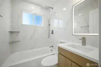 Beautiful large panel tiles on every wall are softened by a warm wood tone vanity w/ a a quartz countertop.