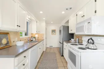 Just beyond the fridge is the hallway that leads to three main floor bedrooms, a full bath, and the stairs to the lower level.