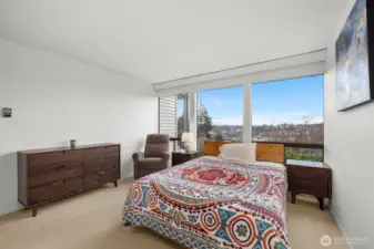 Peaceful primary bedroom retreat with wall-to-wall windows and panoramic neighborhood views.