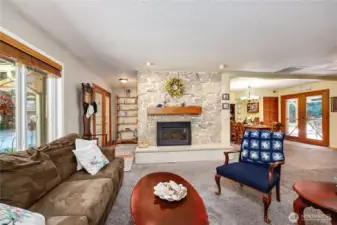 The view from the living room looking back toward the front entry featuring the propane fireplace with stone surround and the dining room on the right. Note the French doors from the dining room to the covered deck.