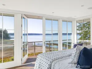 In the private, luxurious primary suite, corner walls of glass open to a wraparound deck—an extension of the room itself. The tide is out in this photo!