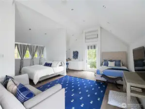 The second primary suite, located in its own private wing and accessed by a private staircase, features vaulted ceilings, a large sitting area, kitchenette, ¾ bathroom, and a balcony overlooking the lush green yard and gardens.