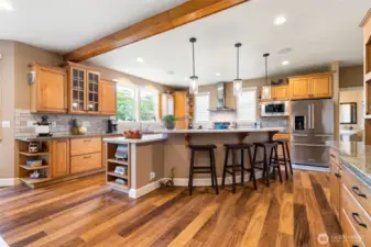 Chef's kitchen with large island. Right of frame is a beautiful custom built-in hutch.