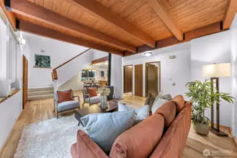 Walls of windows invite views of the lush landscape into this inviting living space, anchored by a cozy wood stove and accented with stylish, earthy furnishings. The harmony of natural light and exposed beams adds rustic charm to everyday living.