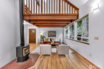 From beneath the mezzanine, this view captures the true essence of the home: nature outside every window, warmth at the hearth, and a layout designed for connection.