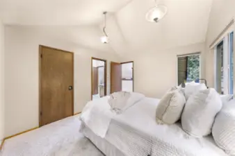 The spacious primary bedroom offers elevated privacy with access to both bathrooms and the sunroom loft. Vaulted ceilings, dual closets, and peaceful outdoor views complete the retreat.