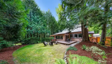 Fully fenced and shaded by evergreens, the backyard offers space to roam or gather. The spacious deck, firepit, and hot tub make it ideal for relaxing or entertaining outdoors.