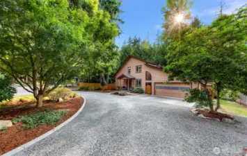 Framed by vibrant landscaping and lush trees, the welcoming front approach is both charming and functional. The gravel drive and landscaped walkway lead to a custom wood-accented entry.