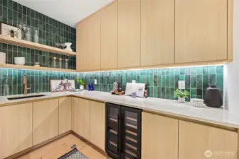 Luxury walk-in butler's pantry- complete  with wine fridge, sink, built in shelving and cabinetry tied together with stunning backsplash tile that goes from counter to ceiling