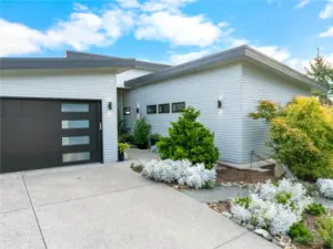 Modern lines with a metal roof and mature landscaping.