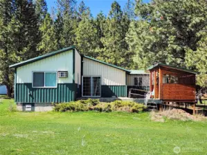 View of rear of the home. Notice the deck and the enclosed area for sitting or outdoor BBQing!