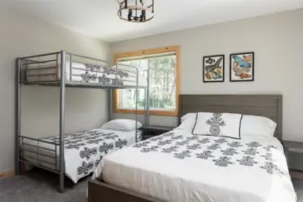 Main floor bedroom featuring a queen bed and twin bunks, and window. (Bedroom #4)