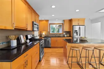 Updated timeless design kitchen with natural wood shaker cabinets, stainless steel appliances and large island with seating