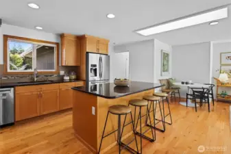 Updated timeless design kitchen with natural wood shaker cabinets, stainless steel appliances and large island with seating