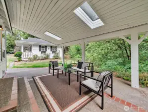 Covered outdoor patio with skylights and forest backdrop