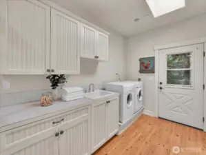 Laundry room with washer, sink, and ample cabinet storage