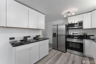 Designer kitchen with granite surfaces, custom tile backsplash, abundant cabinetry and upscale finishes
