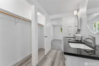 Luxury main-level retreat with oversized closet and en-suite bath complete with granite counters, dual sinks, jetted tub, and stylish lighting