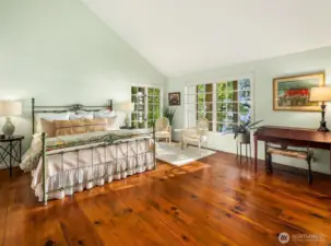 Primary bedroom with vaulted ceilings and old growth reclaimed Douglas Fir 10 inch wide plank flooring.