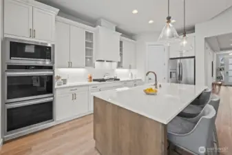 Upgraded kitchen view showcasing the spacious walk-in pantry, stainless steel refrigerator, and custom cabinetry, designed for both style and storage within this open-concept newer construction home in McCormick Trails, Port Orchard.