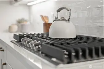 Close-up of the gas cooktop within the upgraded designer kitchen, offering precision cooking alongside quartz countertops, custom cabinetry, and elevated newer construction finishes in McCormick Trails, Port Orchard.