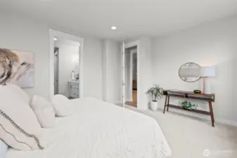 Primary bedroom just off the main living area with a view into the private ensuite bath, highlighting the ease of single-level living and thoughtful layout within this upgraded newer construction home in McCormick Trails, Port Orchard.